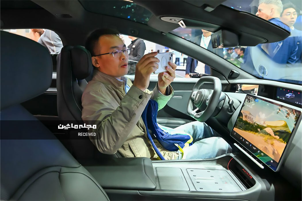 یک بازدیدکننده از داخل خودروی آواتار در طی نمایشگاه خودرو گوانگژو 2023 عکس می‌گیرد